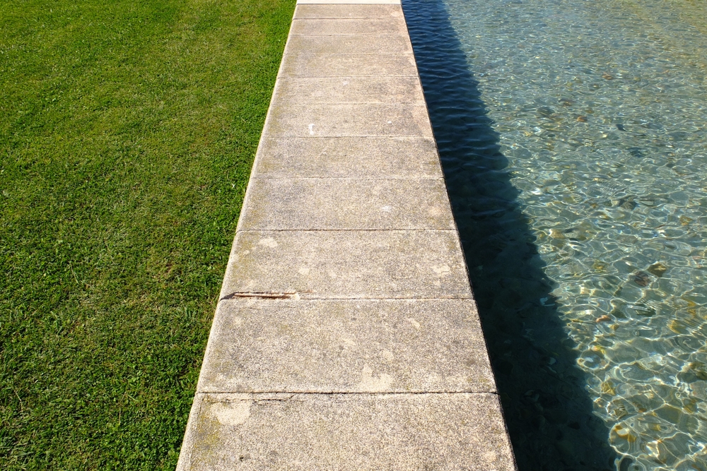 Concrete,Curb,With,A,Pool,And,Grass,On,The,Sides.